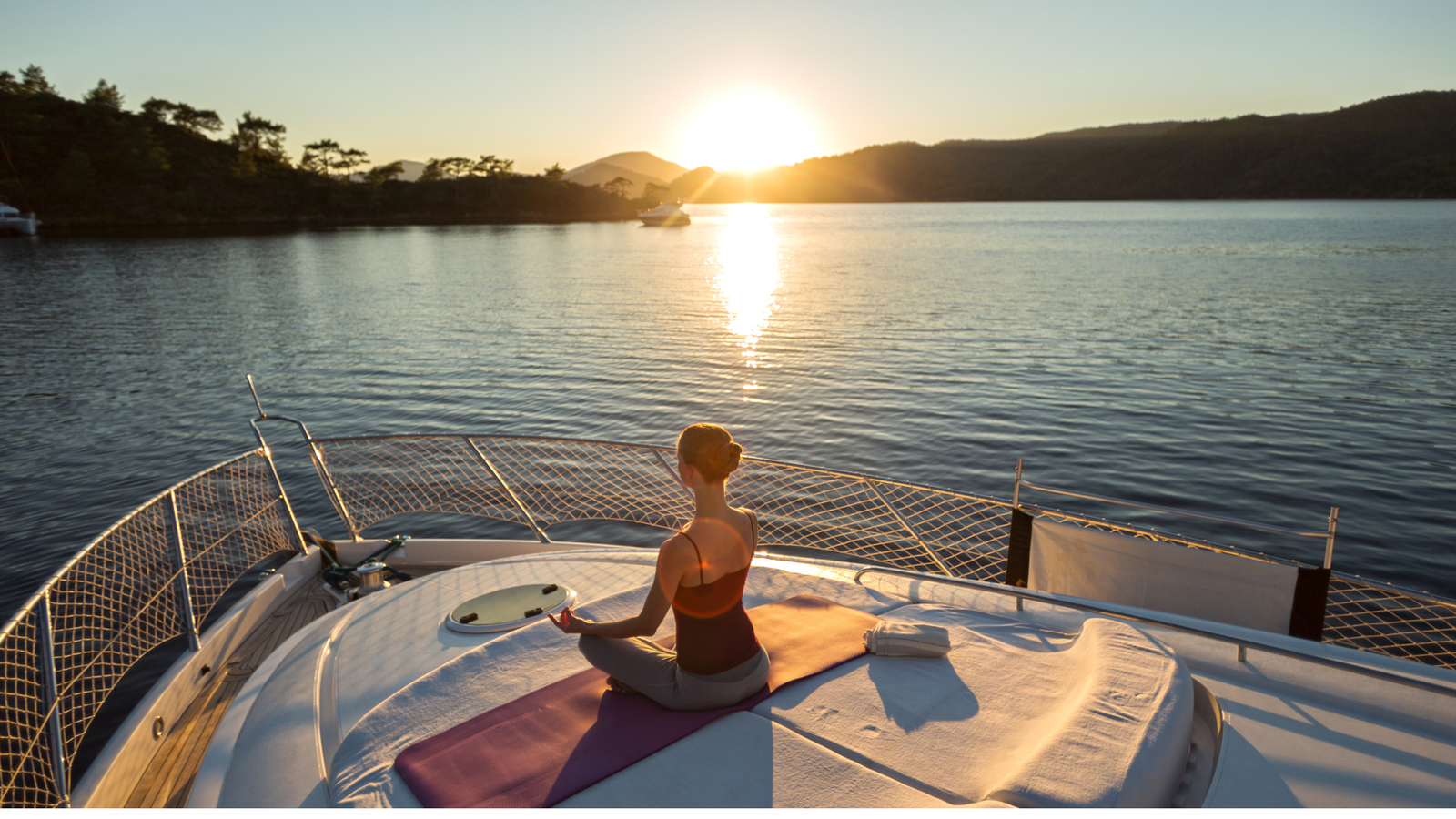 woman meditating in a yacht at sunset