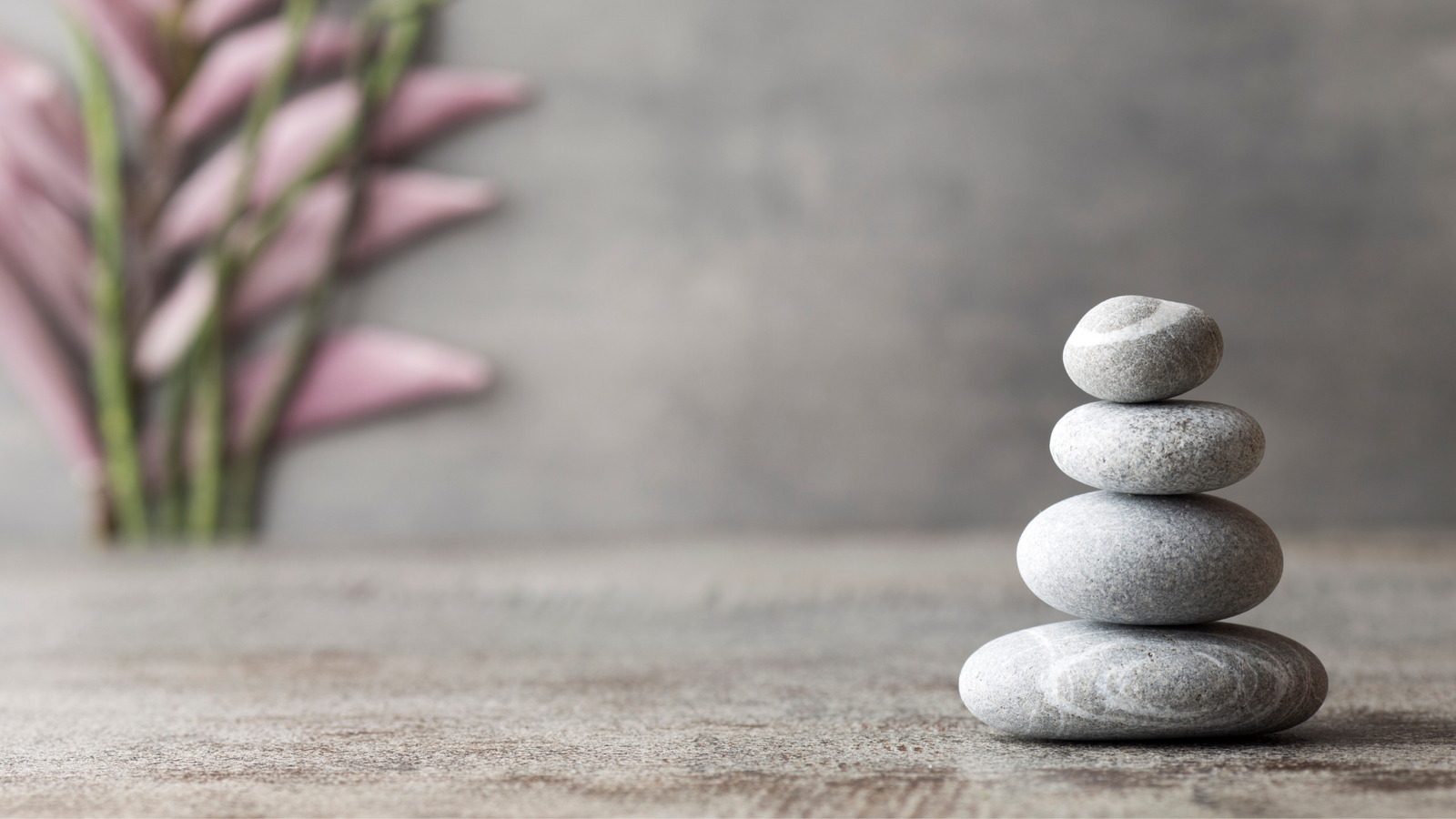 PILE OF ROCKS ON A CONCRETE TABLE TOP AND FLOWERS IN THE BACKGROUND